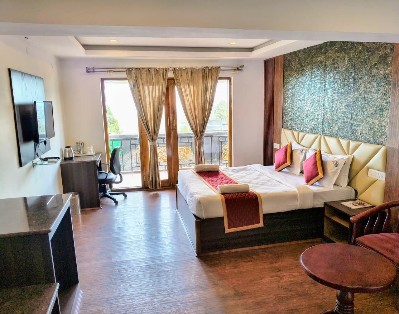 A hotel room with a bed, desk, chair, and a television.