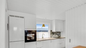 A modern kitchen with white cabinetry, a built-in oven, a sink, and a window with a view of the outside. - "Alvia" - 250m from the sea by Interhome (Løkken)