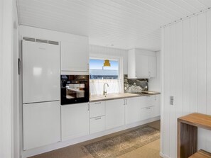 Eine moderne Küche mit weißen Schränken, einem eingebauten Ofen, einer Spüle und einem Fenster mit Blick nach draußen.