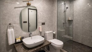 A modern bathroom with a granite countertop, a white sink, a toilet, and a glass-enclosed shower. - OPO Horizon Anant Ayodhya (Faizabad)