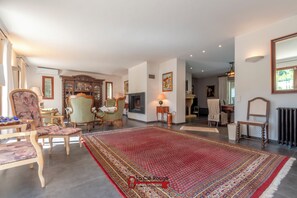 Ein geräumiges Wohnzimmer mit einem großen, rot gemusterten Teppich, Holzmöbeln und einem Kamin.