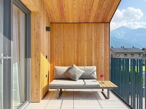 A wooden deck with a sofa and cushions, overlooking a mountain landscape. - Glacier Loft Kitzsteinhorn 1 by Interhome (Zell am See)