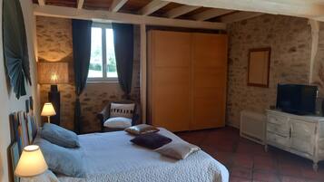 Une chambre à coucher comprenant un lit, une table de chevet, une lampe, une chaise, une armoire et un téléviseur.