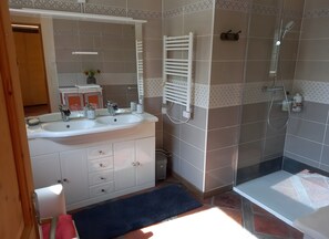 A bathroom with two sinks, a mirror, a towel rack, and a shower.