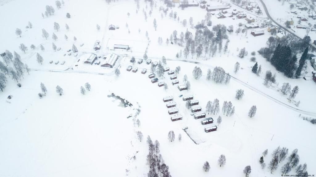 An aerial view of a snow-covered area with several buildings and a road.