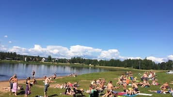 Un encuentro junto al lago, con gente descansando sobre el césped y junto al agua.