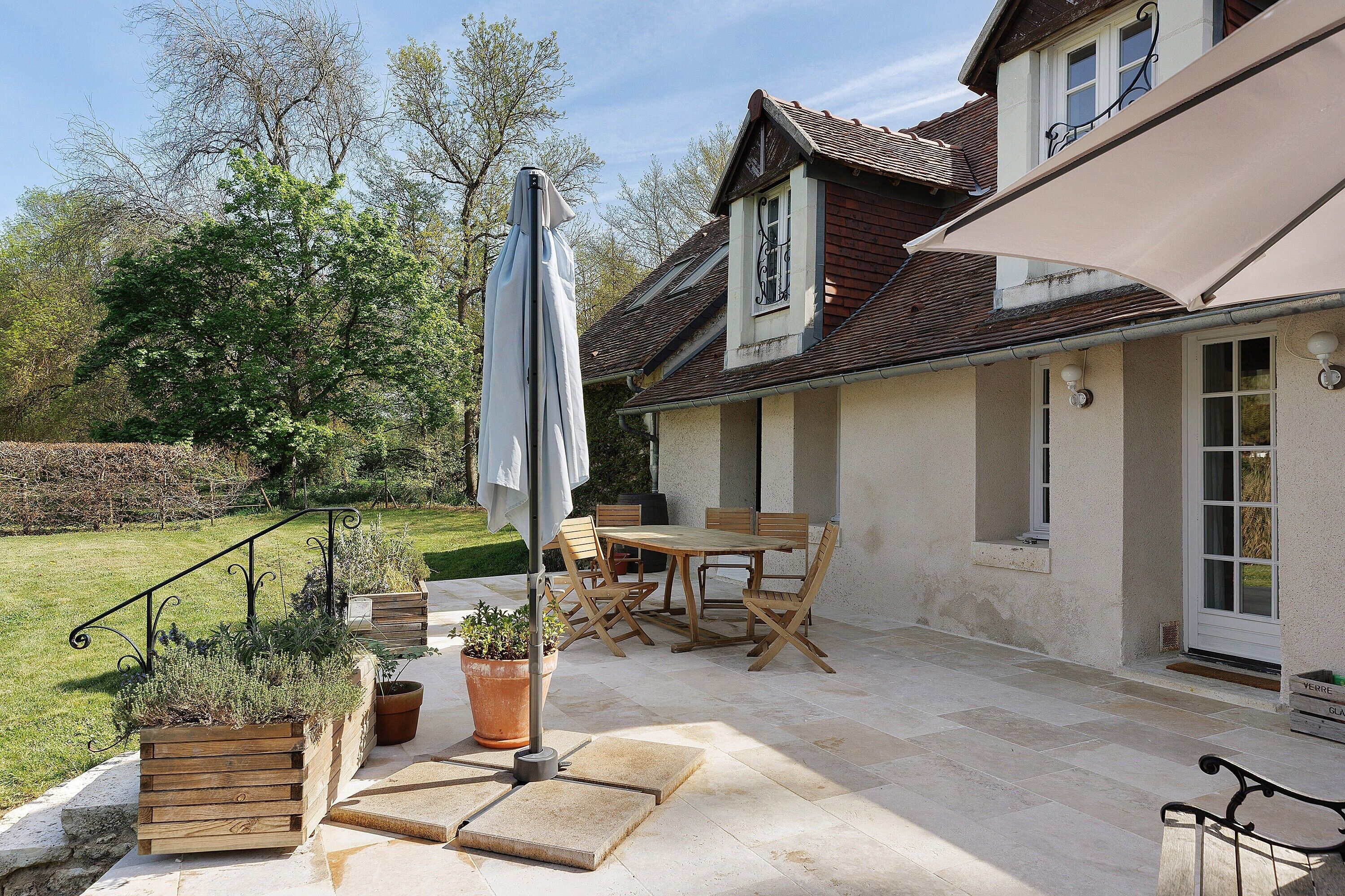 Un patio con mobiliario exterior, una pérgola y plantas en macetas.
