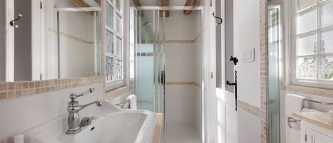 A bathroom with a large bathtub, a shower enclosure, and a window.