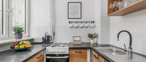 Una cocina moderna con estufa a gas, horno, pileta y un bol de frutas en la encimera.