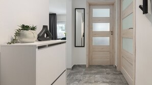 A hallway with a white cabinet, a potted plant, a mirror, and a wooden door with frosted glass panels. - Lumina cozy 3-room apart near the metro (Warsaw)