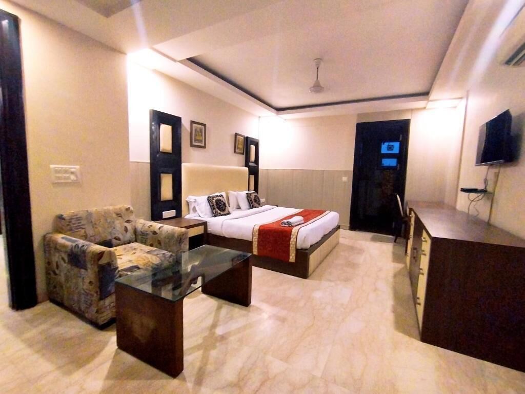 A hotel room with a bed, sofa, and a glass coffee table.