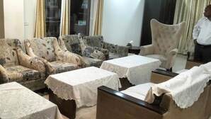 A seating area with patterned sofas and tables covered with lace tablecloths. - Aaron Harikanta  Stayz (New Delhi)