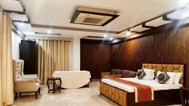 A bedroom with a bed, a chair, a small table, and a sofa. - Aaron Harikanta  Stayz (New Delhi)