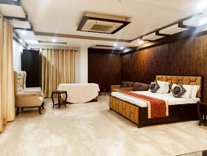 A bedroom with a bed, a chair, a small table, and a sofa. - Aaron Harikanta  Stayz (New Delhi)