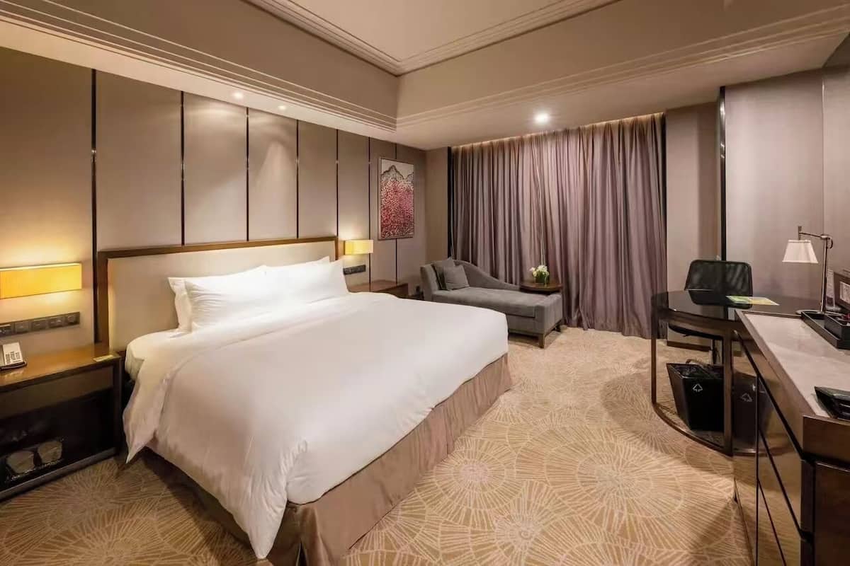 Une chambre d’hôtel avec un grand lit, un bureau, une chaise et un canapé.