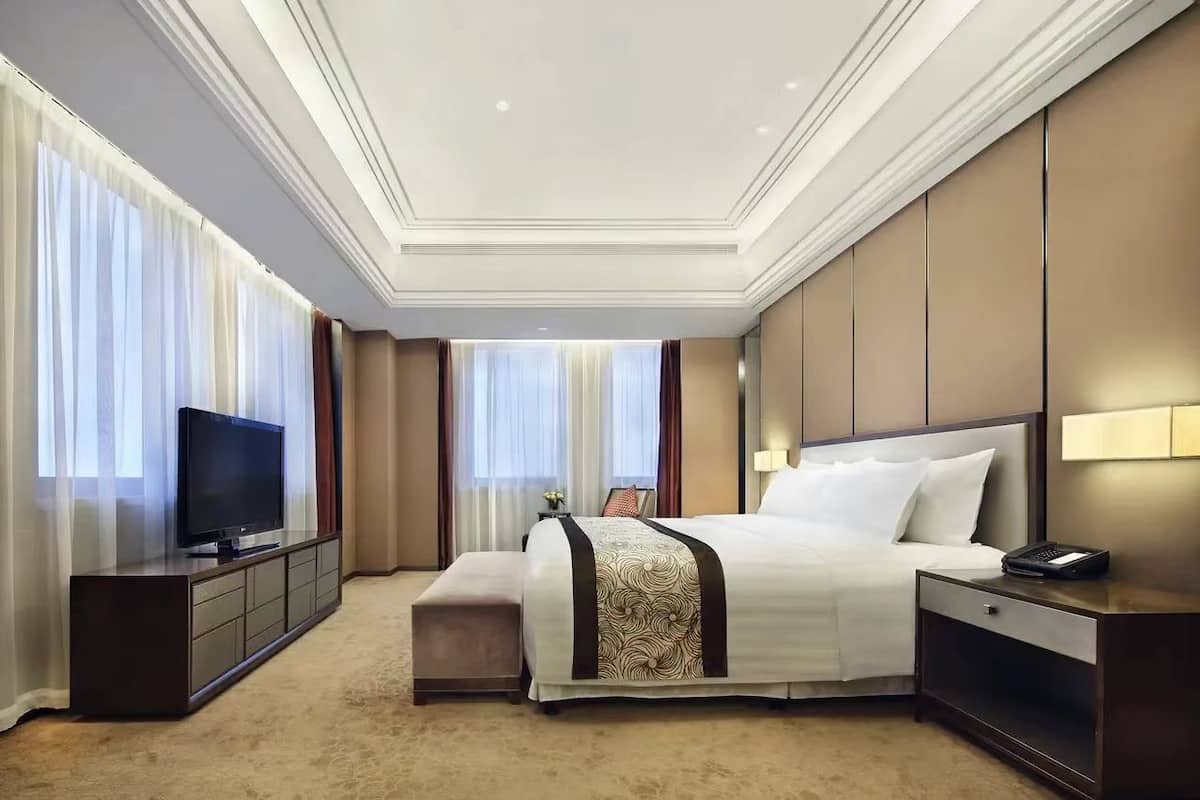 Une chambre d’hôtel avec un grand lit, une télévision, une table de chevet et une commode.