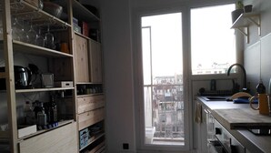 Una cocina con armarios de madera, una ventana y vistas a edificios.