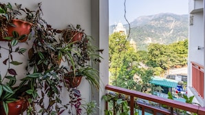 A balcony with potted plants and a view of a mountainous landscape. - LiveAway Rishikesh Laxman Jhula by PACK (Rishikesh)