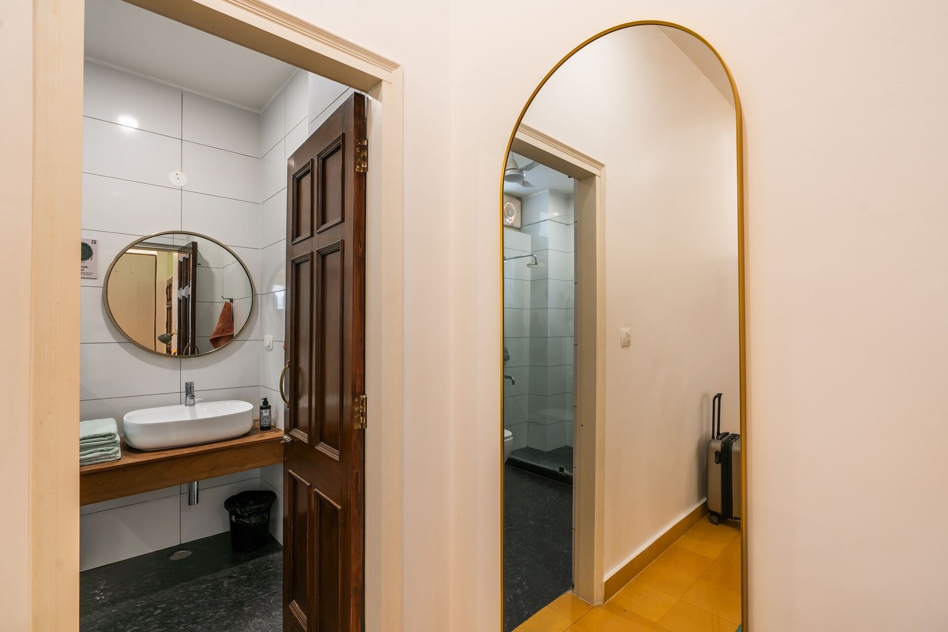 A bathroom with a white sink, a round mirror, and a wooden door.