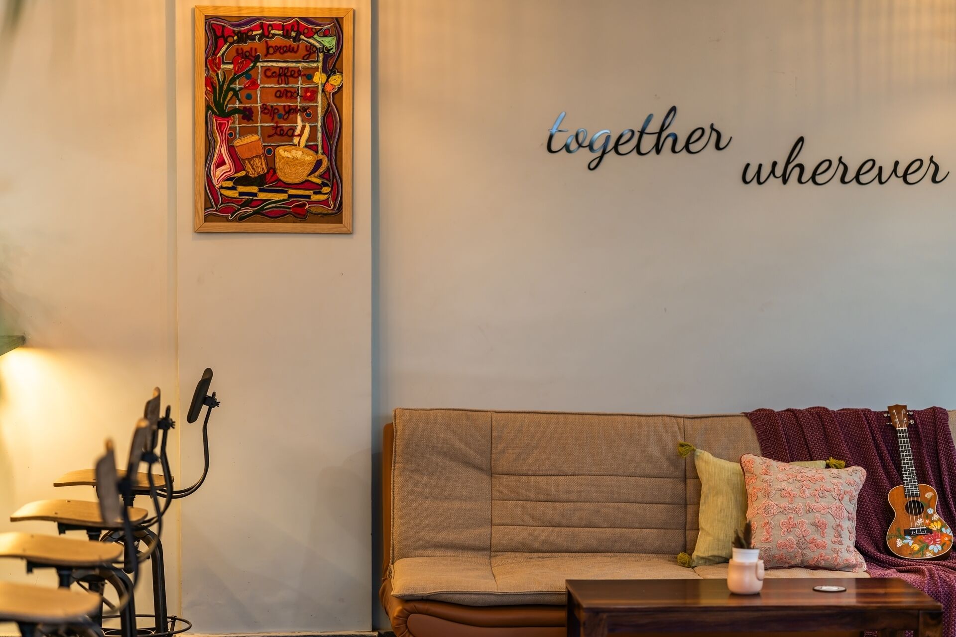 A cozy living area with a sofa, a guitar, and a wall with the phrase "together wherever".