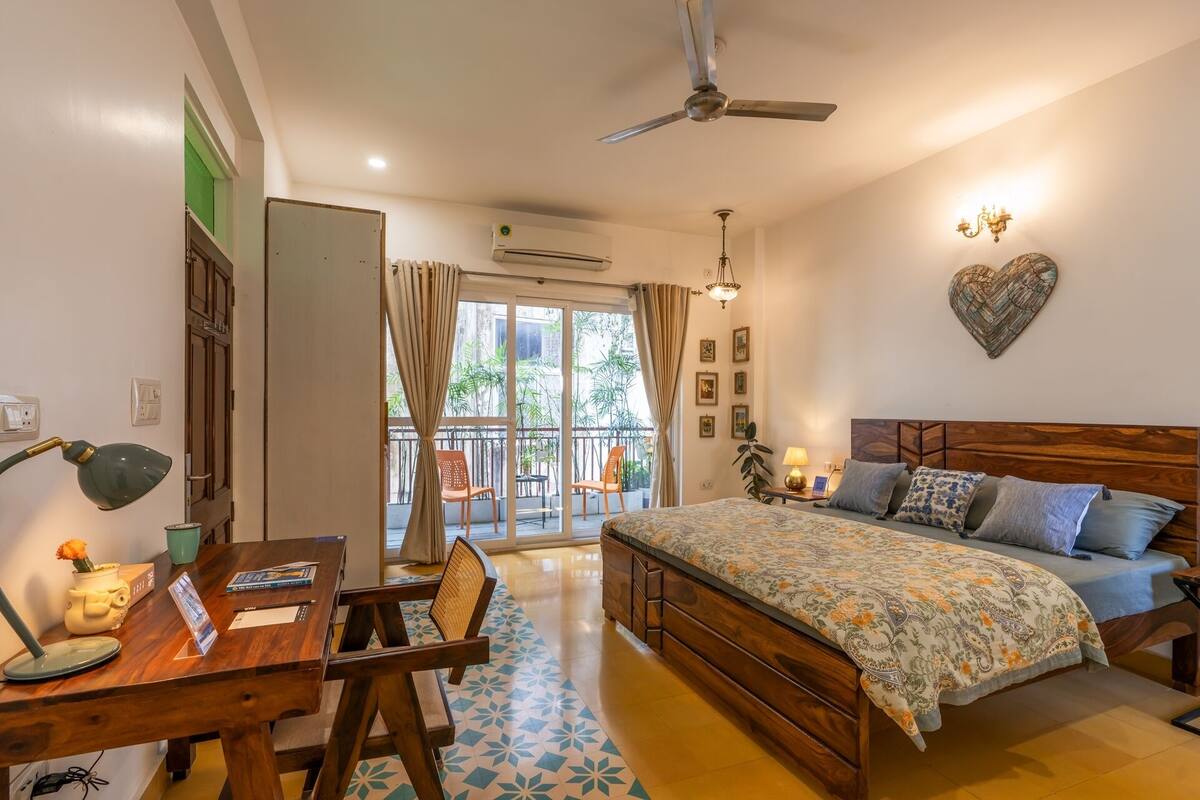 Ein Schlafzimmer mit Bett, Nachttisch, Lampe und Blick auf den Balkon.