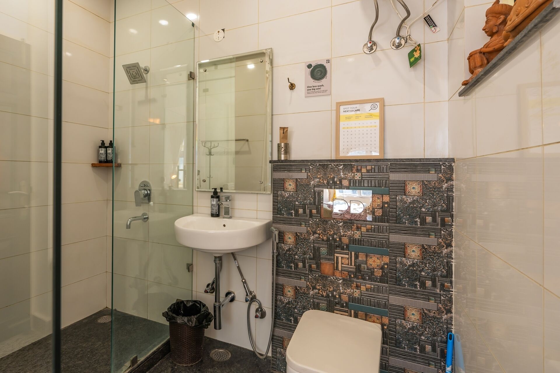 A bathroom with a glass shower enclosure, a white sink, and a toilet.