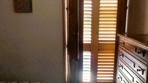 A room with a wooden door, a dresser, and an air conditioning unit on the wall. - Grandma Maria's House - The whole house for you (Scilla)