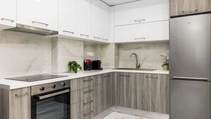 A modern kitchen with white cabinets, a built-in oven, a stainless steel refrigerator, and a marble backsplash. - Eleanor by halu! - 1-BD Apartment next to Hagia Sophia (Thessaloniki)