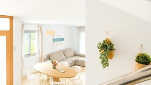 A modern interior with a dining area, a sofa, and two hanging plants.