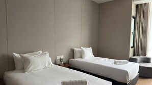 Ein Hotelzimmer mit zwei Betten, einem kleinen Tisch, einem Stuhl und einem Fenster mit Vorhängen.