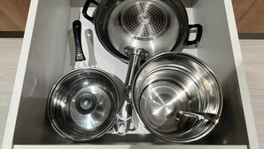 Eine Küchenschublade mit Edelstahlkochgeschirr, darunter Töpfe und Pfannen.