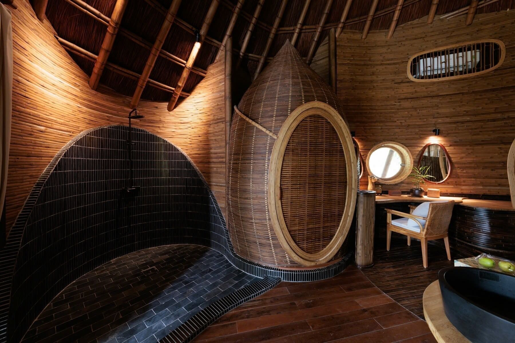 A room with a curved wooden ceiling, a circular seating area, a small table with a chair, and a round mirror on the wall.