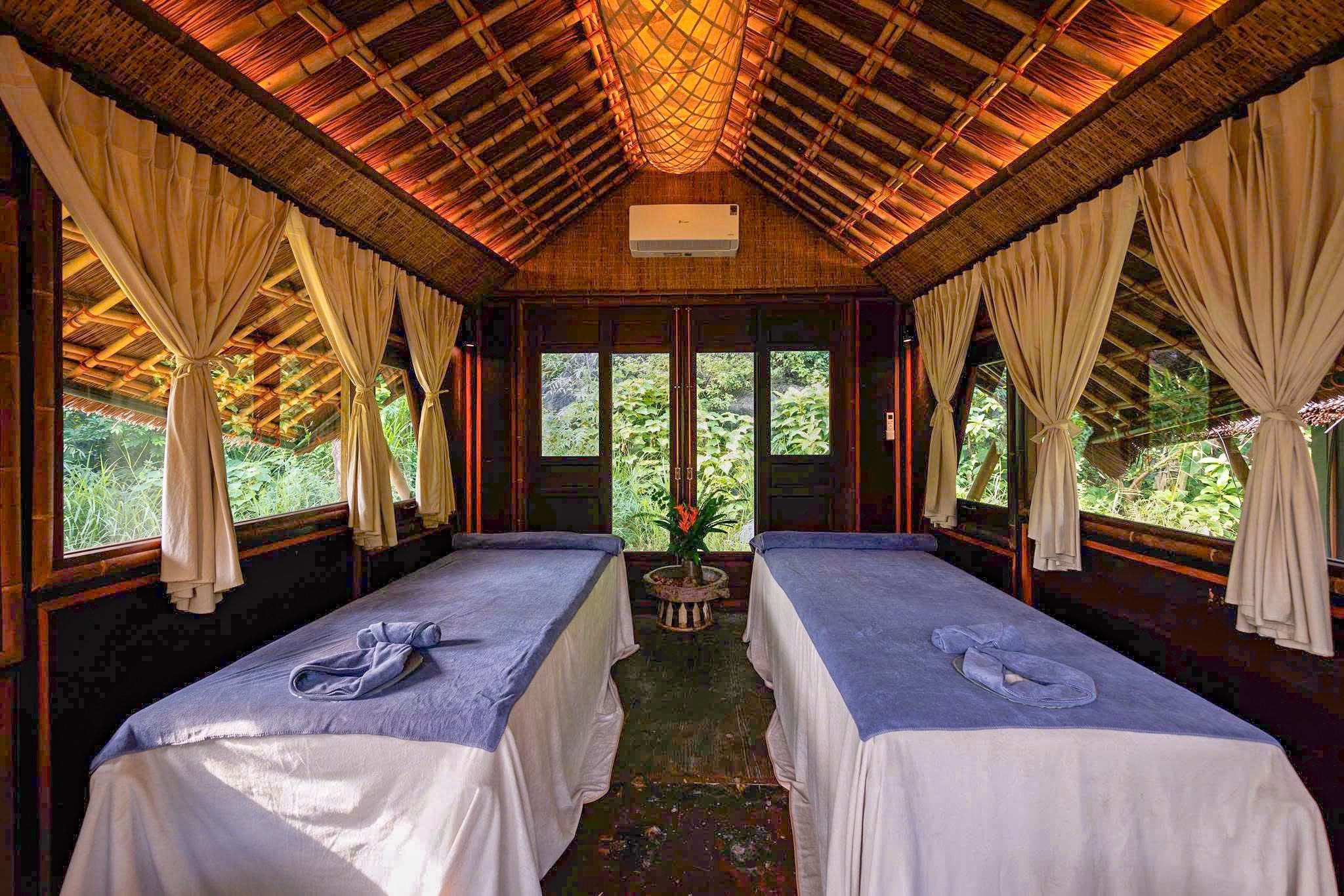 A room with two beds, a ceiling fan, and a window with curtains.