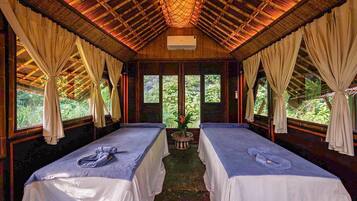 A room with two beds, a ceiling fan, and a window with curtains.