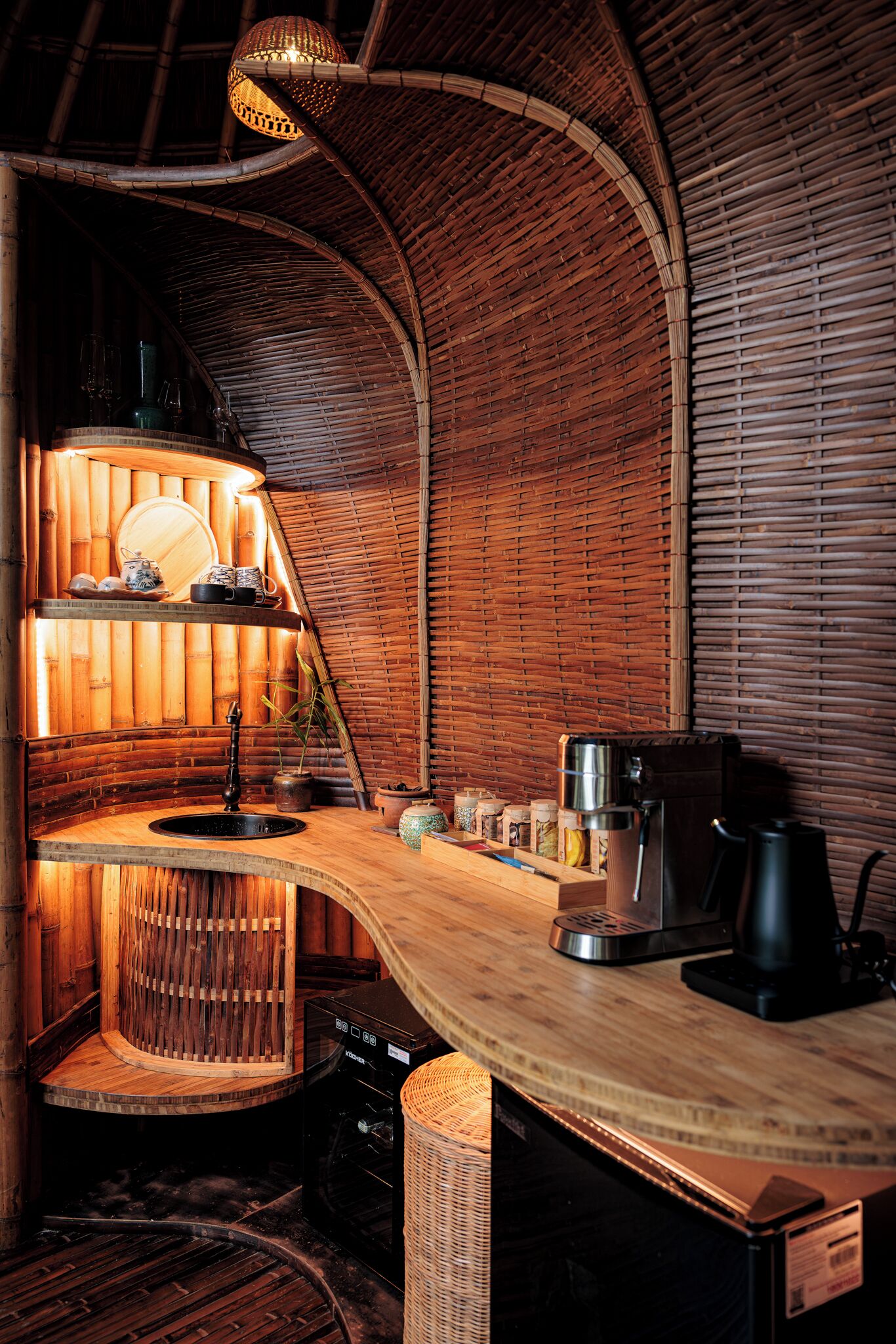 Una cucina accogliente e rustica con un bancone curvo in legno, un lavandino e una macchina per il caffè.