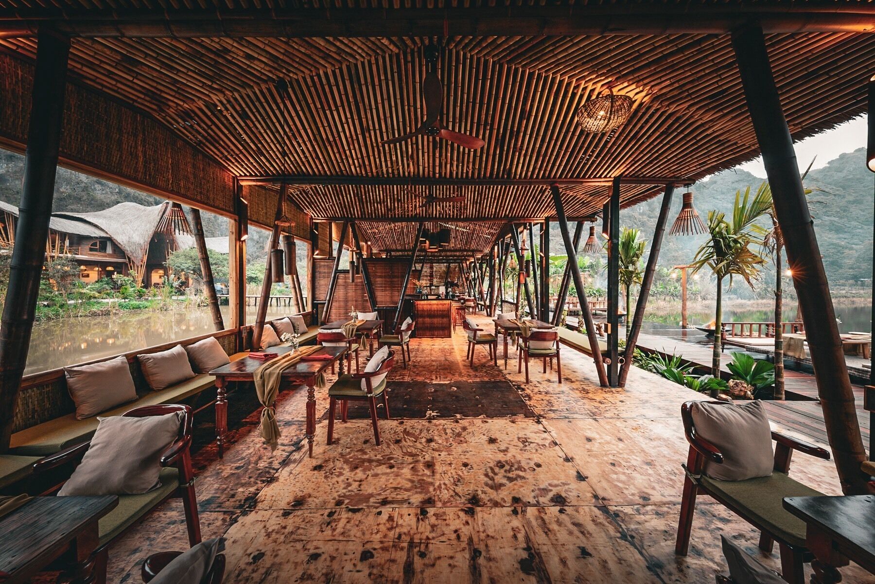 An open-air dining area with wooden furniture and a thatched roof.