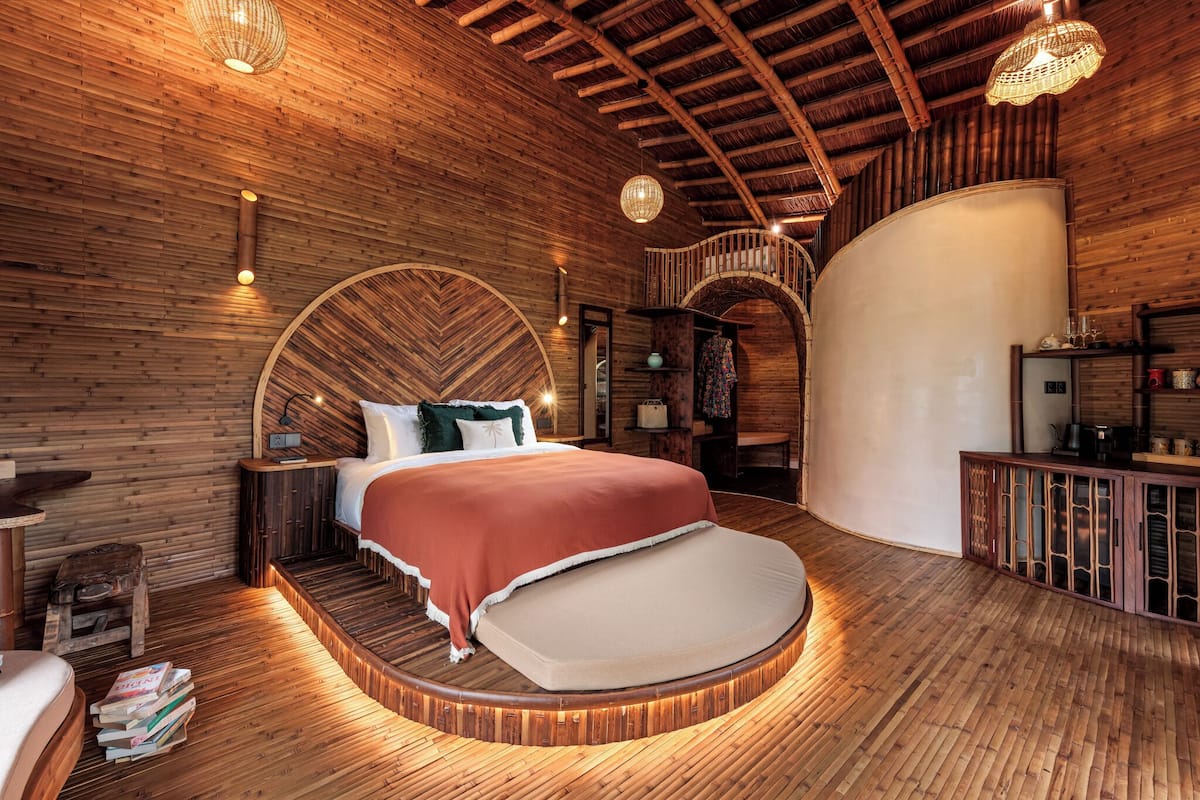 Una cama redonda de madera con cabecera curvada, suelo de madera y techo ondulado.