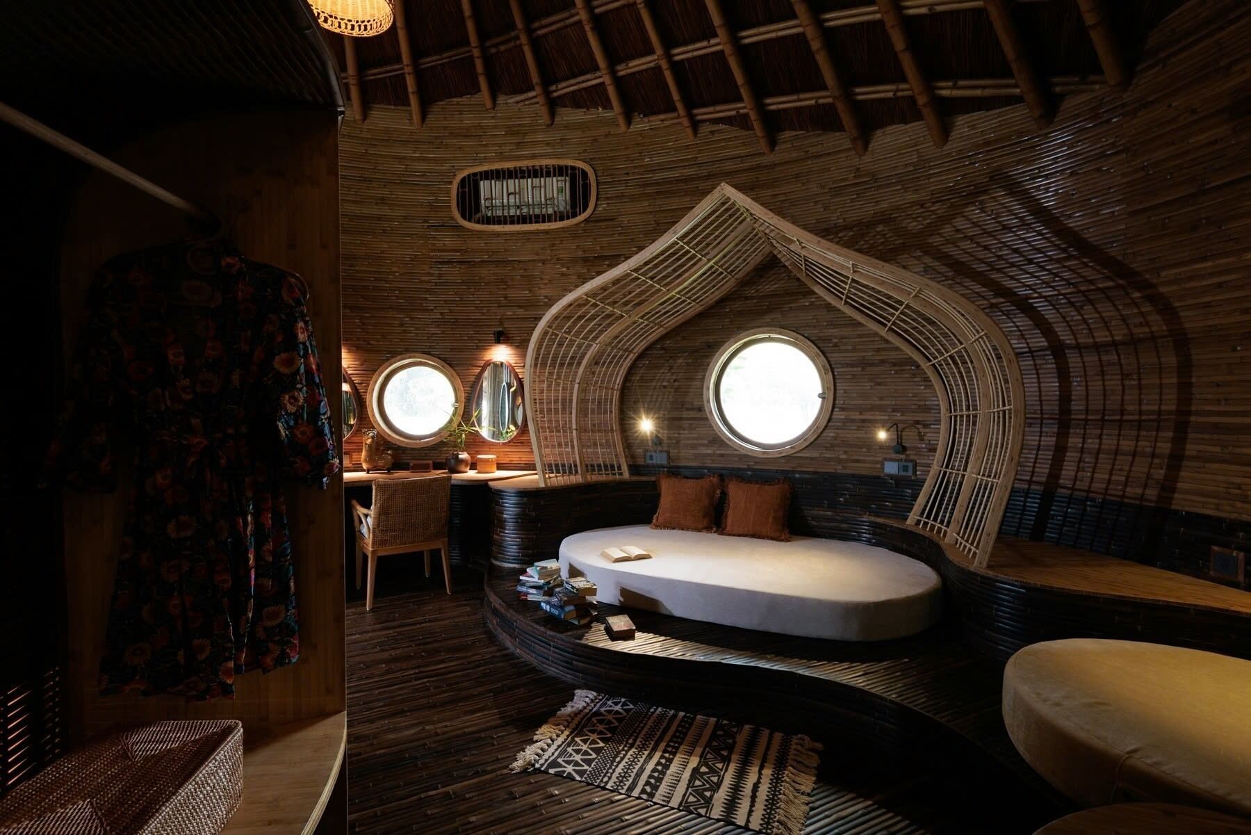 Een knus, rondom kamer met een bed, een klein bureau en een rond raam.