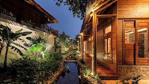 A traditional wooden house with a stone pathway and a small water feature.
