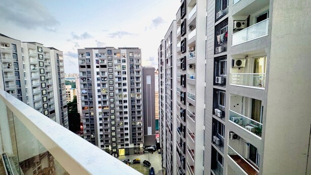 A high-rise residential building with multiple balconies, a parking area below, and a clear sky. - Luxury 1401 Pixiestays With Free Parking (Mumbai)