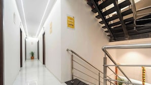 Un pasillo de hotel con una escalera, una planta en maceta y un cartel que indica una zona relacionada con viajes.