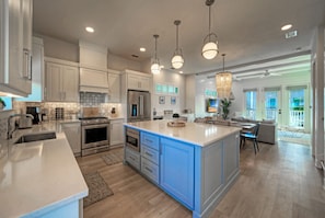 A modern kitchen with white cabinets, a large island, stainless steel appliances, and pendant lighting. - Pool + Boardwalk Access + Steps from the Beach | Villa Blanca by AvantStay (Port Aransas)