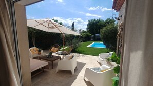 Une terrasse avec des meubles d’extérieur, une piscine et une vue sur le jardin arrière.