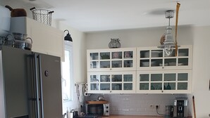 Une cuisine moderne avec des meubles blancs, un réfrigérateur en acier inoxydable, un four à micro-ondes et une machine à café.