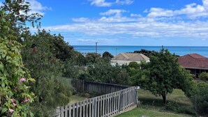 A residential area with a wooden fence, green lawns, and houses with red roofs. - Short walk to the beach and local cafes (Penguin)