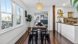 A modern kitchen with white cabinets, a wooden countertop, and a hanging chandelier.