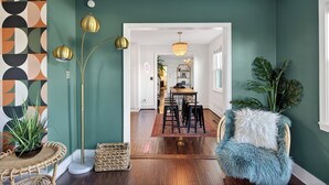 A modern interior with a dining area, a rattan chair, and a large plant.