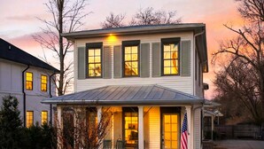 Ein zweistöckiges Haus mit Veranda, Eingangstür und einer amerikanischen Flagge.