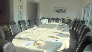 Une salle de conférence avec une longue table, des chaises et un tableau blanc.