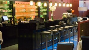Un espace bar avec un comptoir, des tabourets de bar et des étagères remplies de bouteilles.